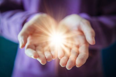 Hands holding a glowing light.