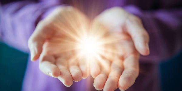 Glowing light held gently in cupped hands.