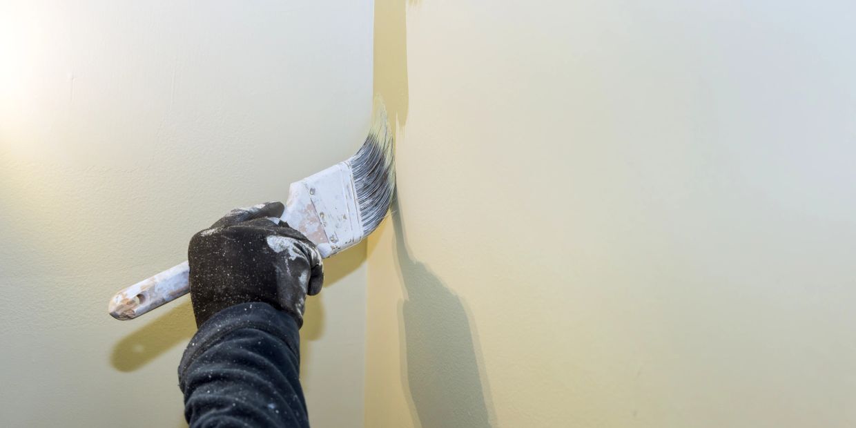 Person painting a wall with a brush.