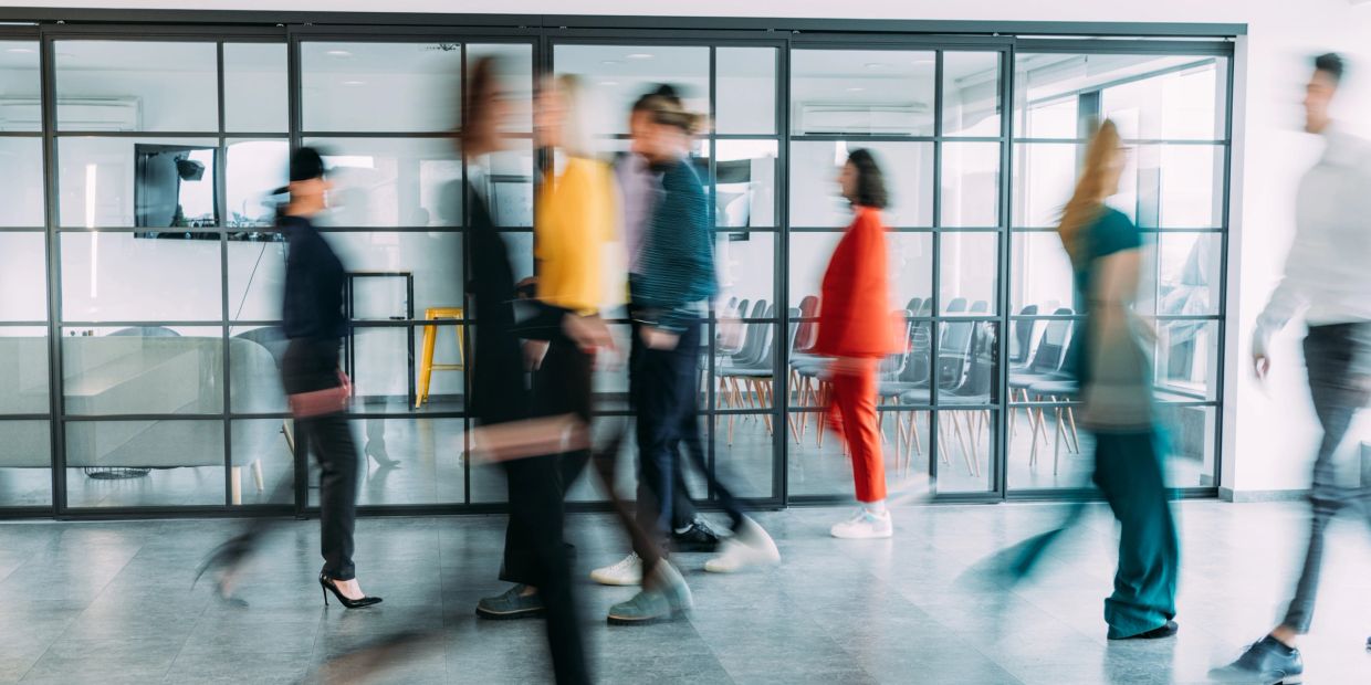 Blurred people walking in a modern office hallway.