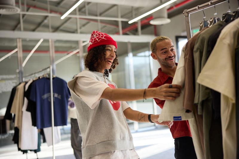 A trendy female store owner helps a young man choose clothes. Customer service