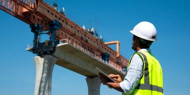 Construction worker inspects a bridge under construction using a tablet.