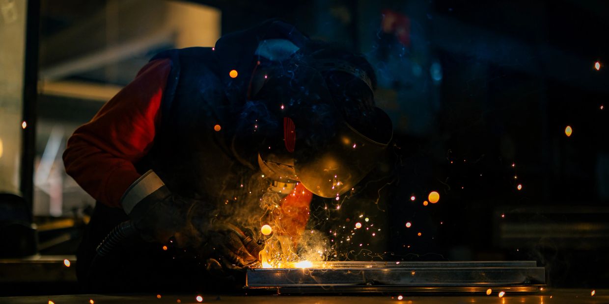 Welder working with sparks in a dark workshop.