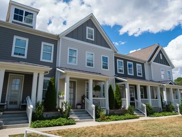 Row of modern townhouses with front porches under a partly cloudy sky.