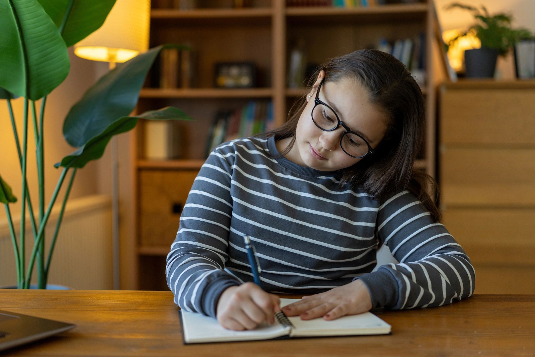 Young girl writing in a notebook indoors.