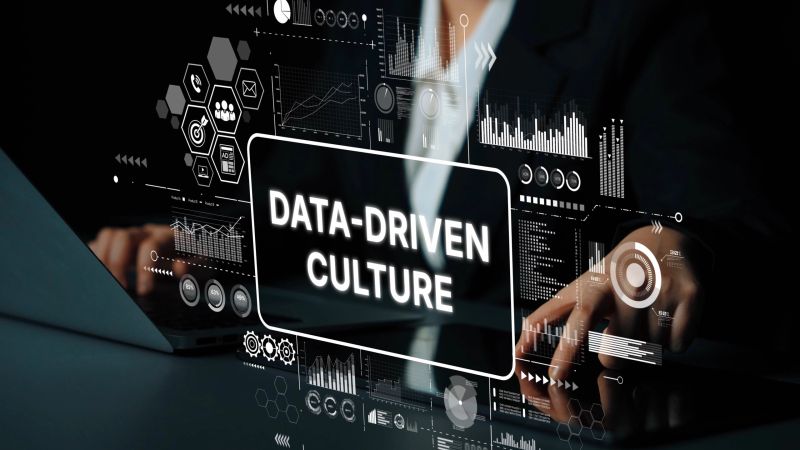 This is a professional photograph that embodies the concept of a data-driven culture within an organization. The image shows a modern workspace with digital screens displaying various charts, graphs, and data-centric icons, emphasizing informed decision-making and strategic planning. It's an excellent visual for business leaders, change management consultants, and articles discussing corporate culture, analytics, and the use of data in strategic operations. The composition highlights the integration of data into everyday business processes.