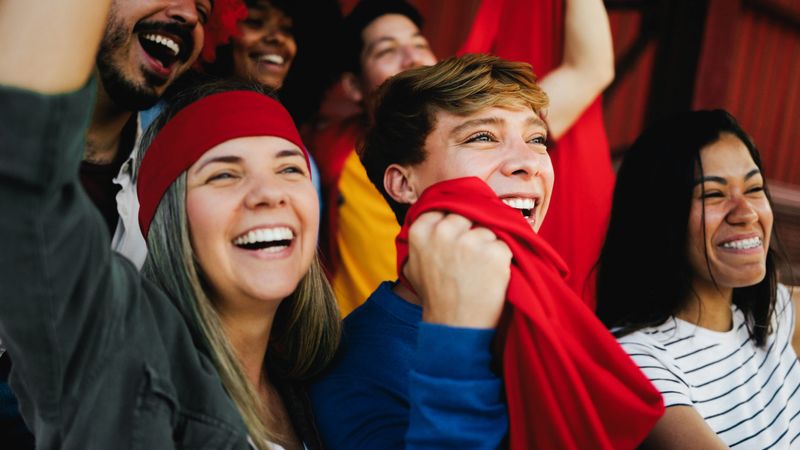 Football fans celebrate during a match while supporting their team - Soccer sport entertainment concept