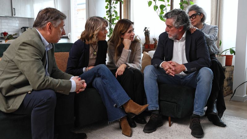 Mature adult friends gathering in a modern living room, having a conversation, sharing moments. Support and togetherness concepts