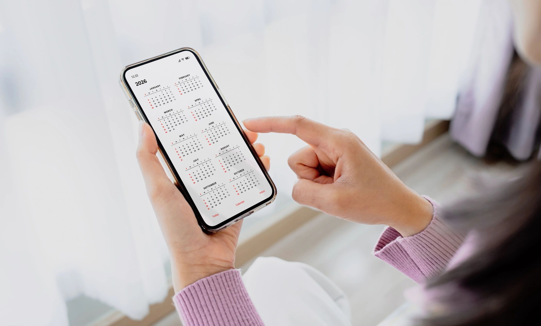 Person holding a phone displaying a 2026 calendar app.