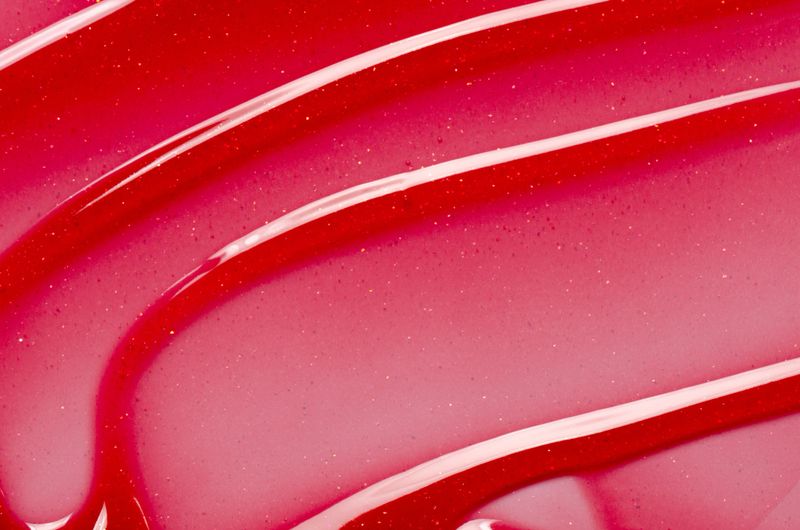 Lip oil, liquid red lipstick. Cosmetic product for lip moisturizing.