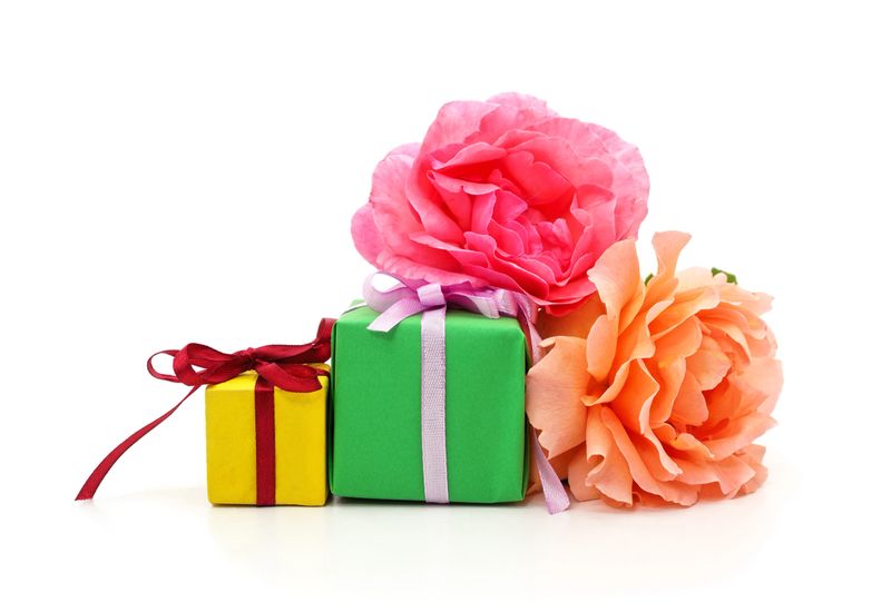 Two small gift boxes wrapped in green and yellow paper with pink and orange roses isolated on a white background.