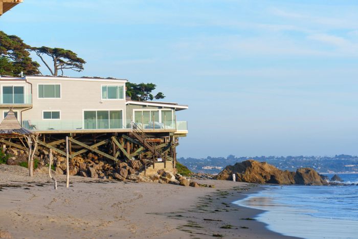 Wooden boardwalk overlooking the ocean with a seagull perched on a post.