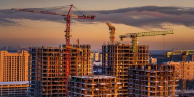 High-rise buildings under construction with cranes at sunset.