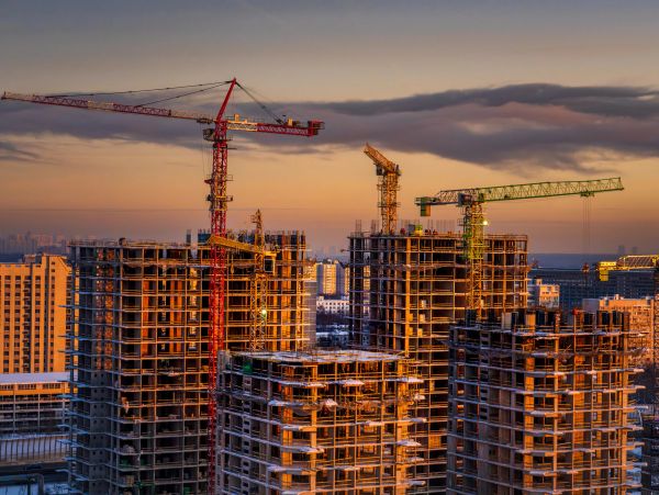 High-rise buildings under construction with cranes at sunset.