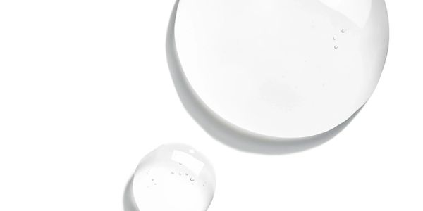 Two clear water droplets on a white surface.