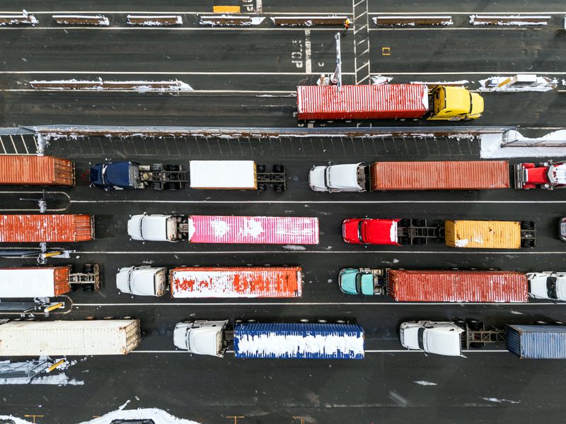 A queue of semi trucks wait to enter a container terminal.