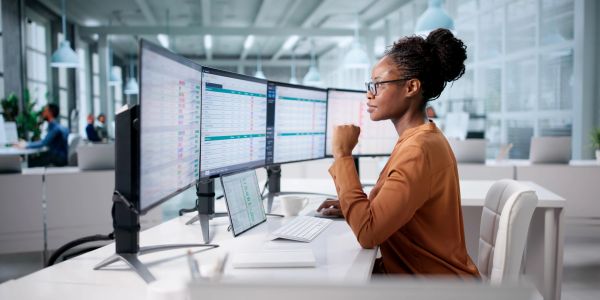 Woman working on multiple monitors in an office.