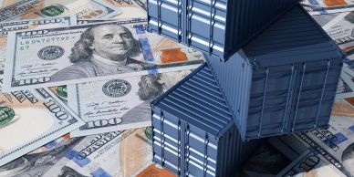 Stacked shipping containers on US dollar bills.