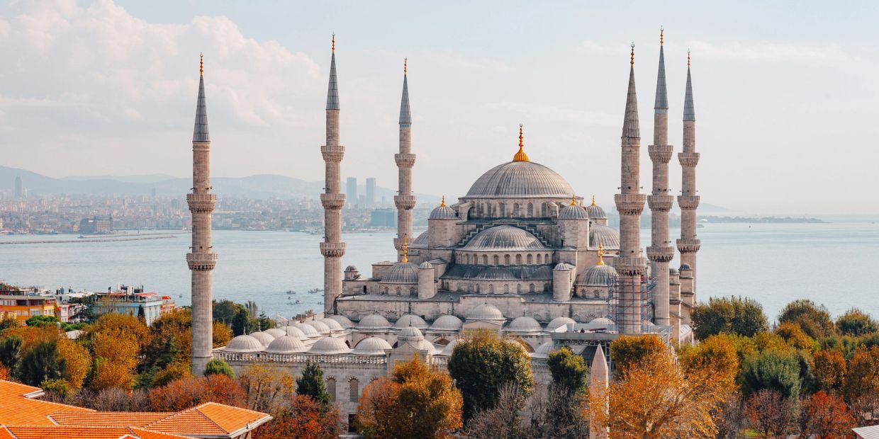A historic mosque with six minarets by the waterfront.