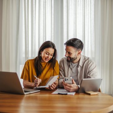 Couple working together with laptops and documents at home.