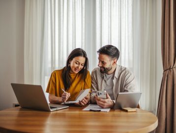 Couple working together at a table with devices.