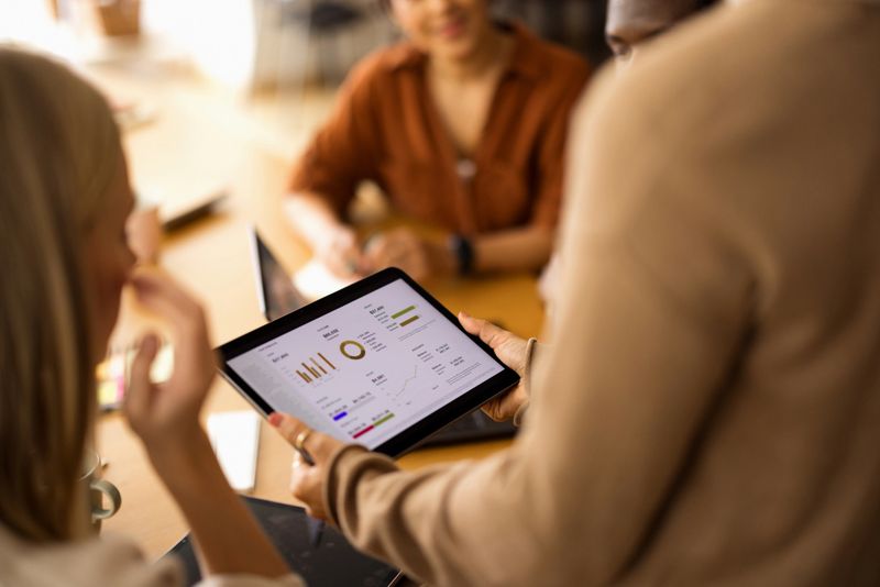 Group of people collaborating and reviewing financial data and charts on a digital tablet during a business meeting