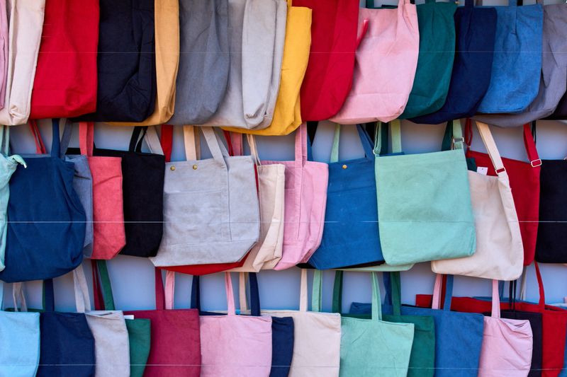 A diverse collection of sustainable corduroy tote bags in various bright colors perfect for retail and fashion lifestyle concepts High quality textile