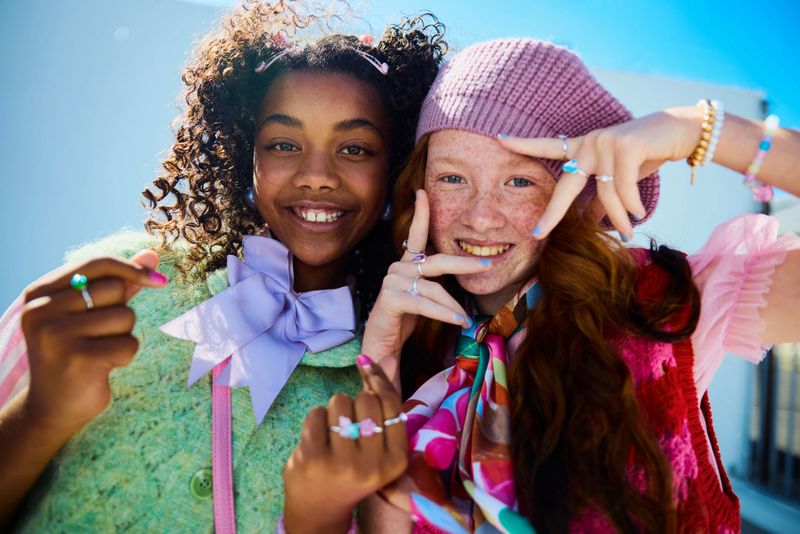 Two cheerful multiethnic girls smiling for the camera outdoors, celebrating youth and diversity