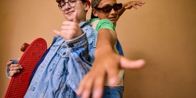 Two young people posing with a skateboard.