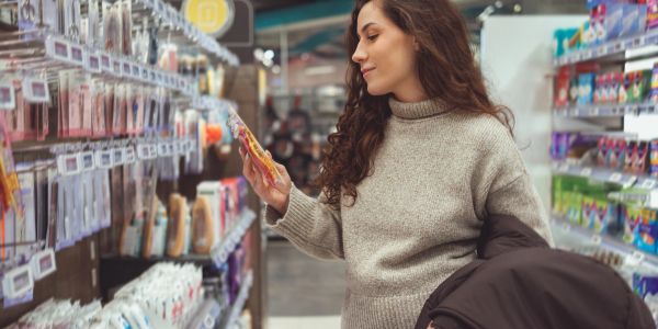 Woman shopping in a store aisle, examining a product.