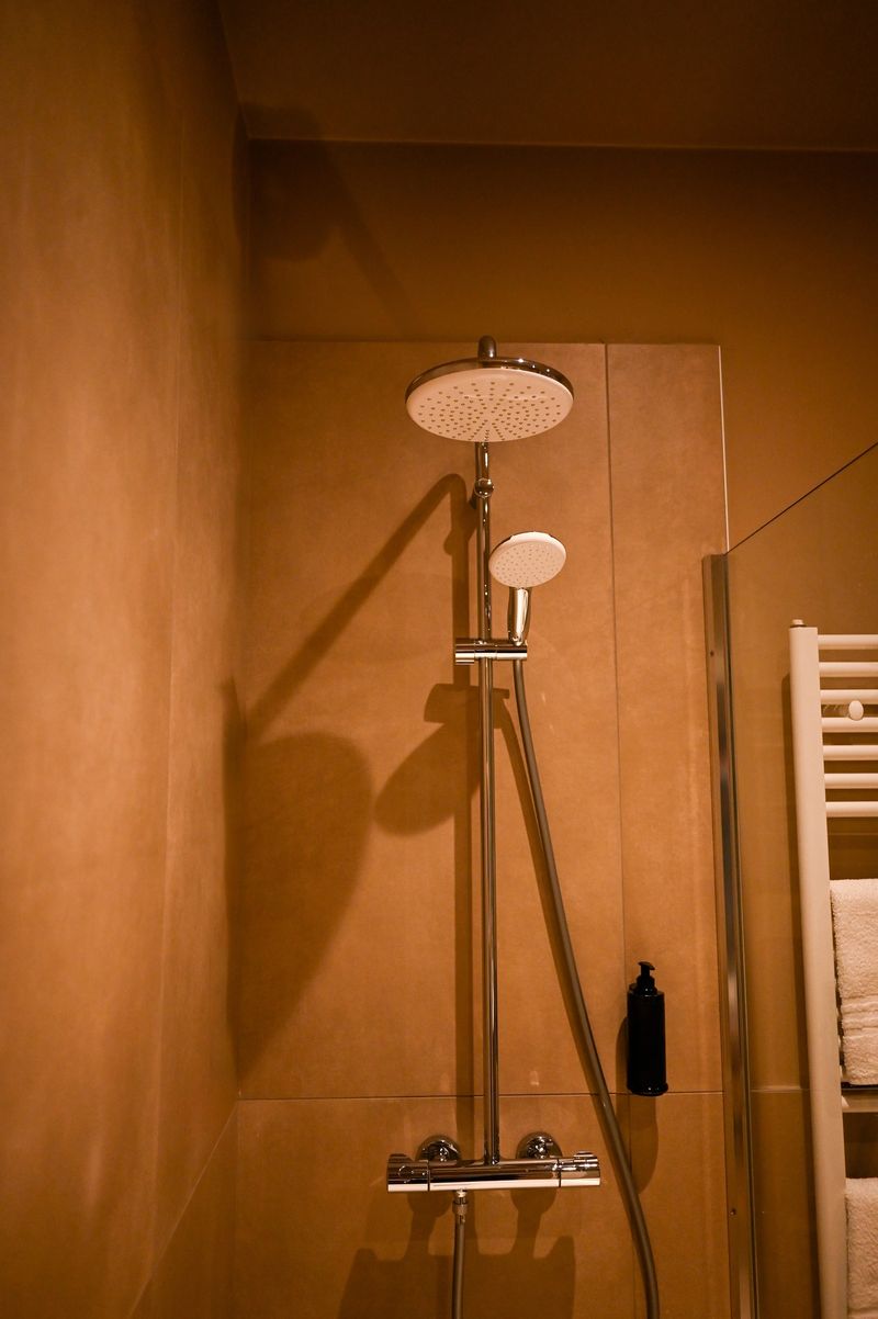 Modern chrome shower head and handheld shower providing water in a tiled bathroom