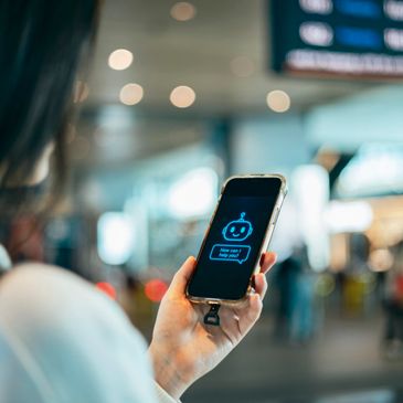 Person holding smartphone with chatbot interface displayed.
