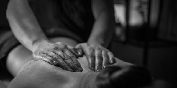 Hands giving a relaxing back massage in a dimly lit room.