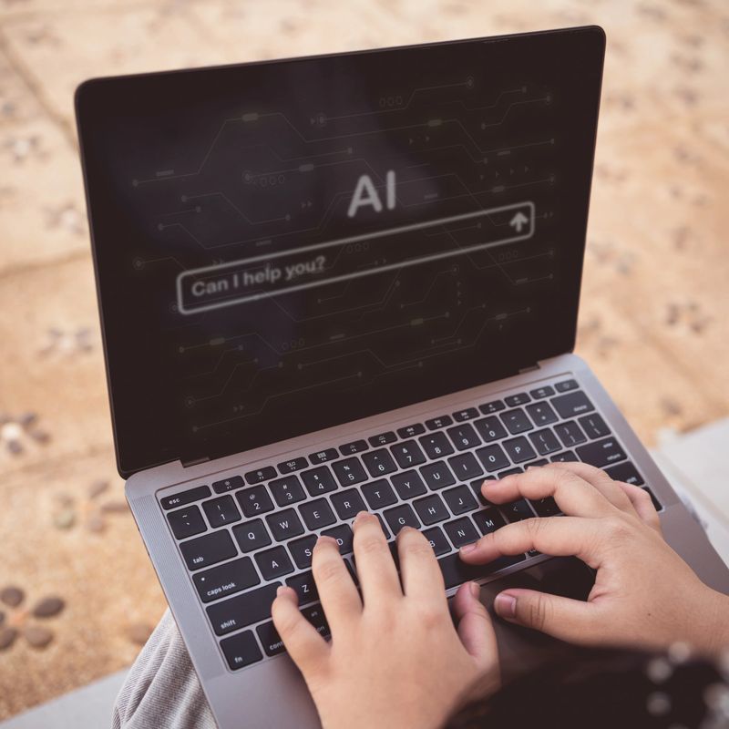 Person typing on laptop keyboard with artificial intelligence AI chatbot interface on screen
