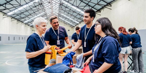 Volunteers sorting clothes in a spacious indoor area.