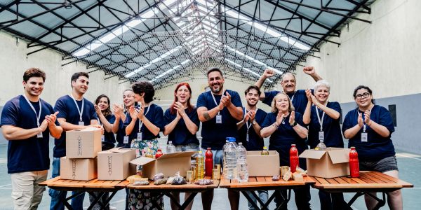 Group of volunteers clapping behind packed food boxes.