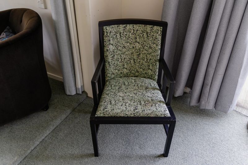Old style seat stands near hanging drapes chair cushion upholstery fabric floral
