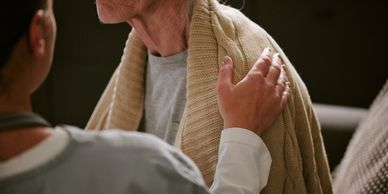 A caregiver comforting a person wrapped in a blanket.