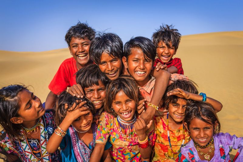 Group of happy Gypsy Indian children playing on a sand dunes - desert village, Thar Desert, Rajasthan, India.