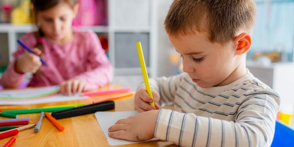 Children engaged in arts and crafts at a colorful table.