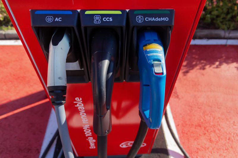 Modern electric vehicle charging station with fast chargers and cables in a city parking lot. Sustainable mobility, clean energy, EV infrastructure and green transportation concept.