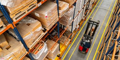 Forklift moving in a large warehouse with stacked boxes.