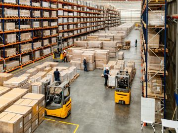 Busy warehouse with forklifts and workers moving boxes.