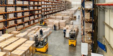 Busy warehouse with forklifts and workers handling packages.