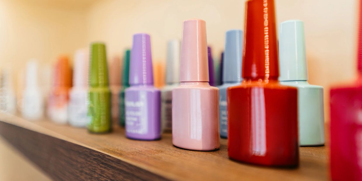 Colorful nail polish bottles lined up on a wooden shelf.