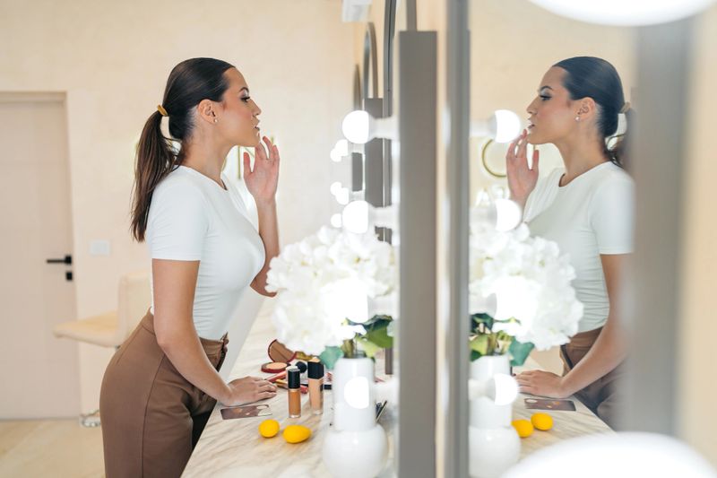 Young woman looking at mirror after getting her makeup done at the beauty salon.