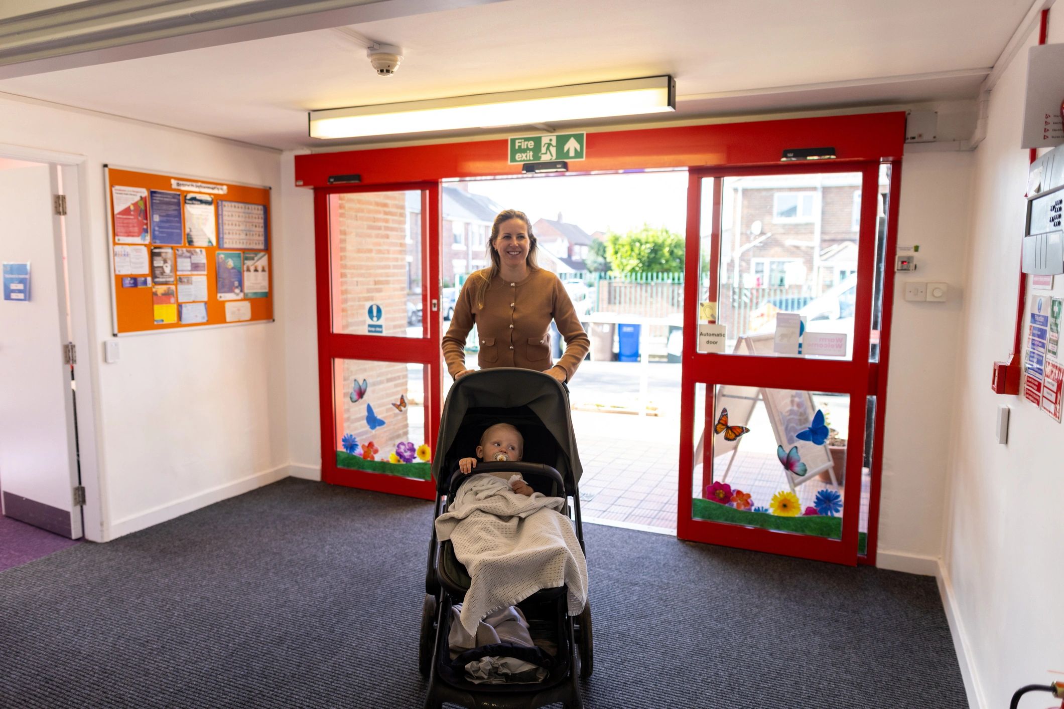 A colorful, welcoming image of smiling parents walking into a bright childcare center.