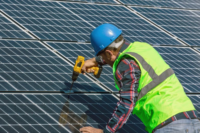 Solar Panel Installation: Installer at Work on Sunny Day at Energy Power Station. Capture the essence of progress in renewable energy with this impactfu photo, showcasing a solar panel installer equipped with a drill in the process of installing solar panels on a solar energy power station. The scene unfolds on a bright and sunny day, symbolizing the harnessing of clean energy from the sun. This image is perfect for conveying the dedication and expertise behind solar panel installation, making it an ideal choice for energy-related promotions, environmental publications, and social media content championing the future of sustainable energy.