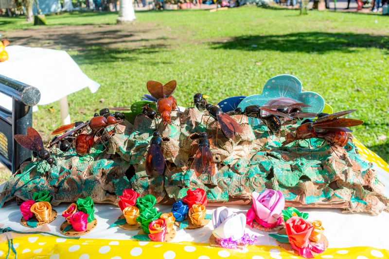 Various colorful insect sculptures and ribbon flowers displayed on a table at a fair