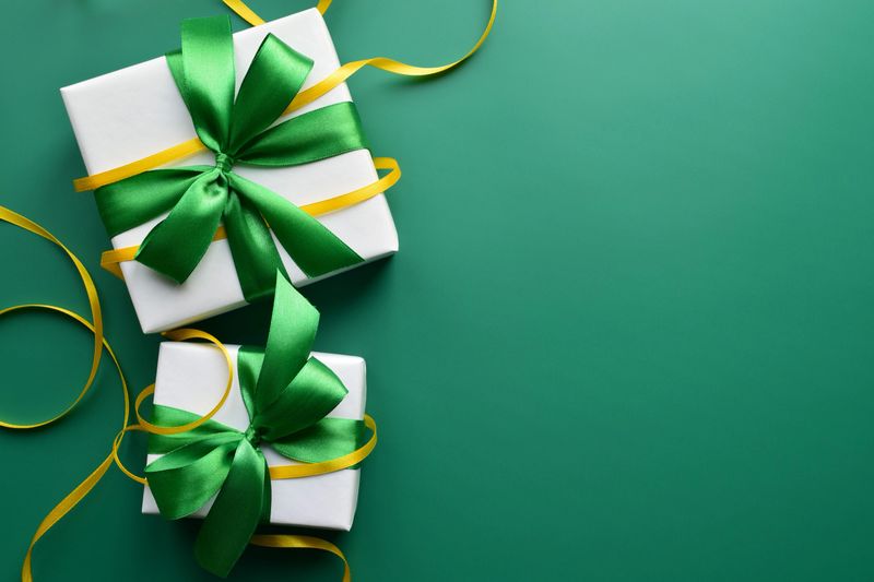 Two gift boxes with green satin ribbon bows on a green background